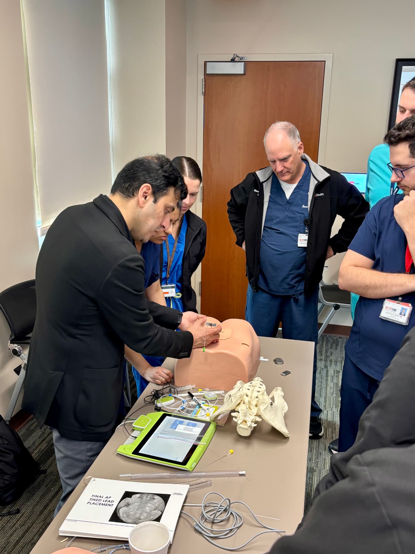 Dr. Farhan leading hands-on sacral neuromodulation simulation training with residents and faculty