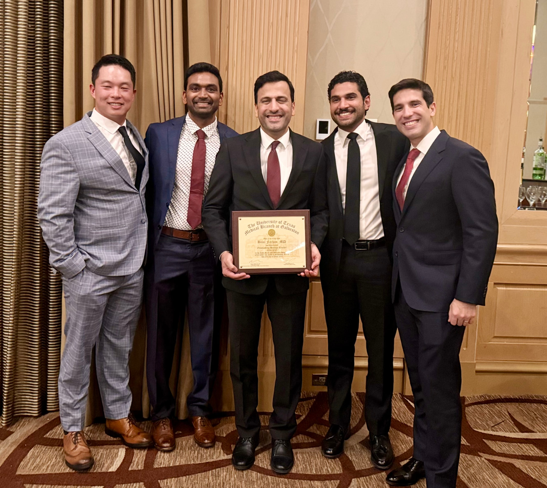 Dr. Farhan holding a UTMB Outstanding Urology Teacher award plaque with colleagues